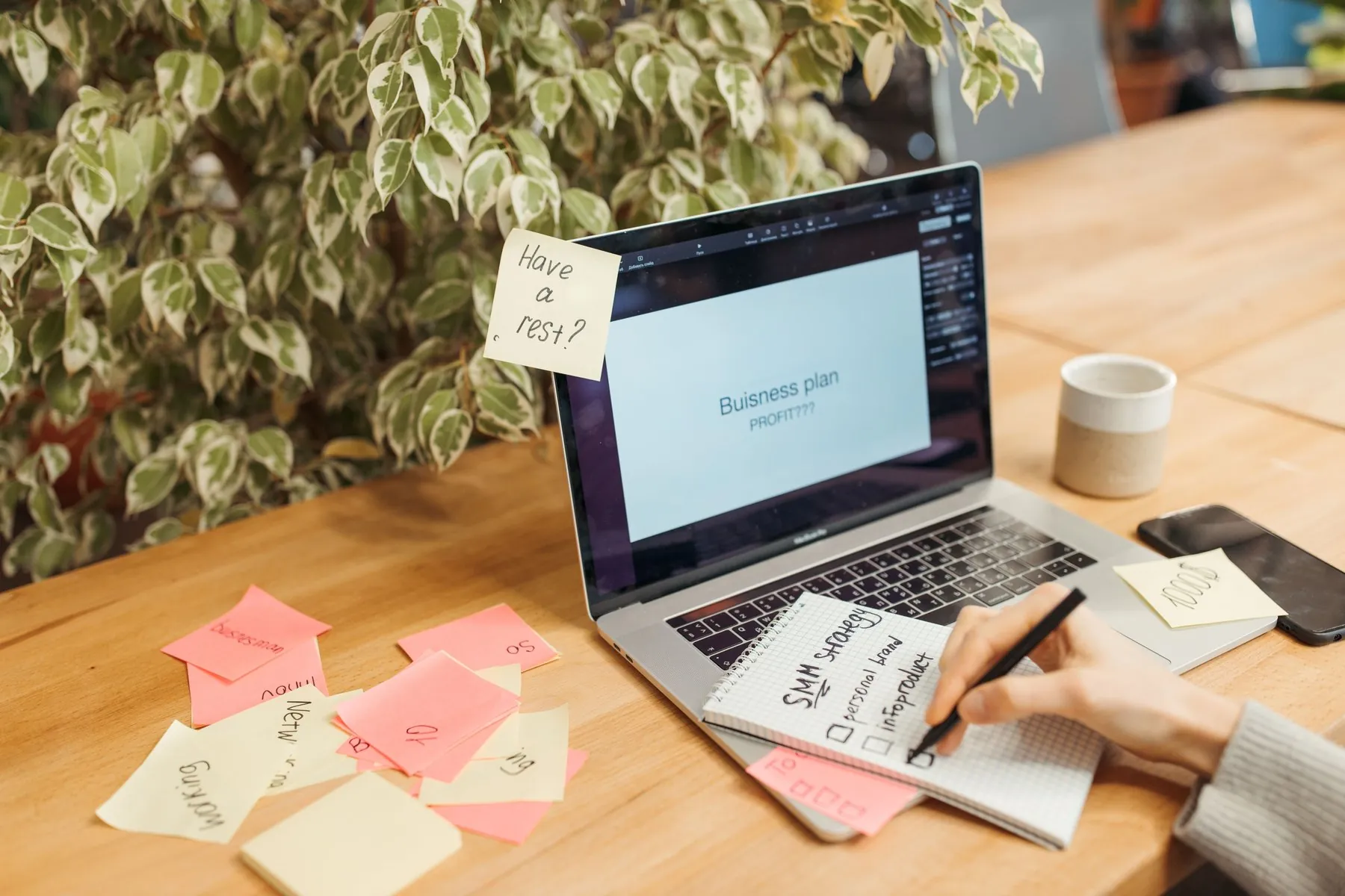 A laptop on a wooden desk with sticky notes, one reading ‘Have a rest?’
