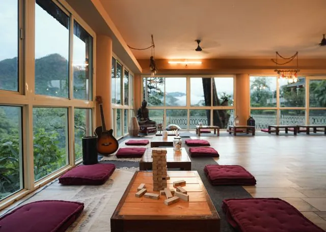 A calm retreat room with floor cushions and wide windows onto misty hills