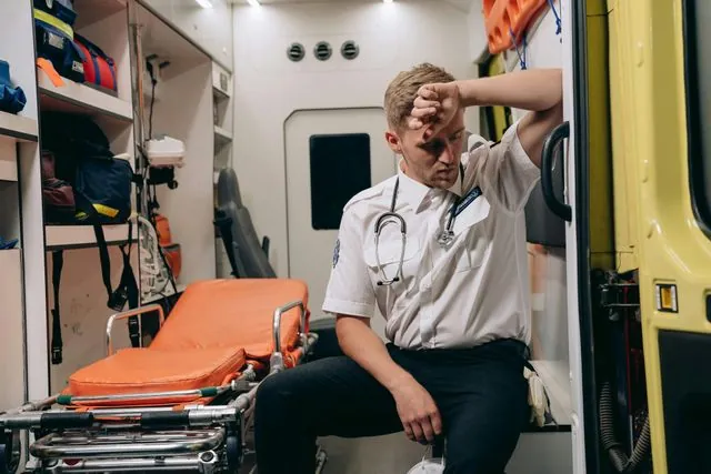 A tired paramedic resting in the back of an ambulance
