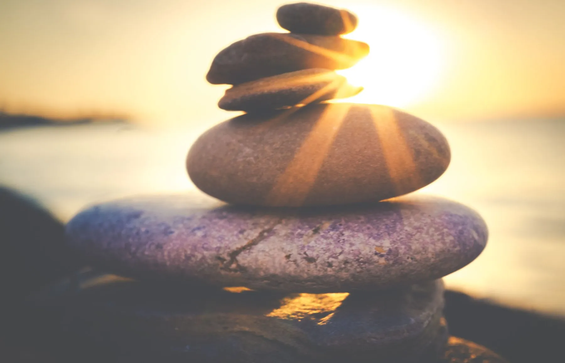 A stack of smooth stones glowing in soft sunlight by the sea