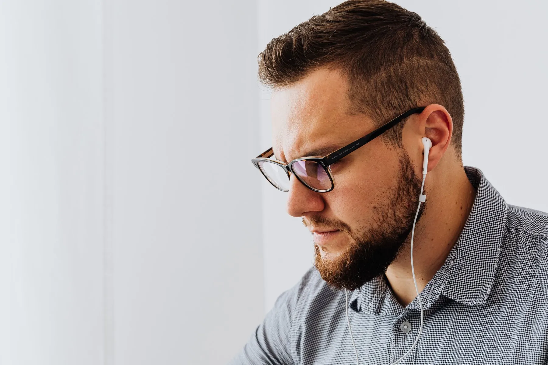 A man in glasses listening through earphones