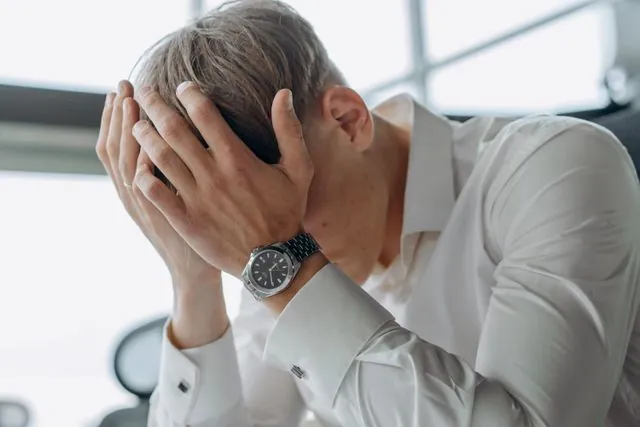 A man in a white shirt with his head in his hands