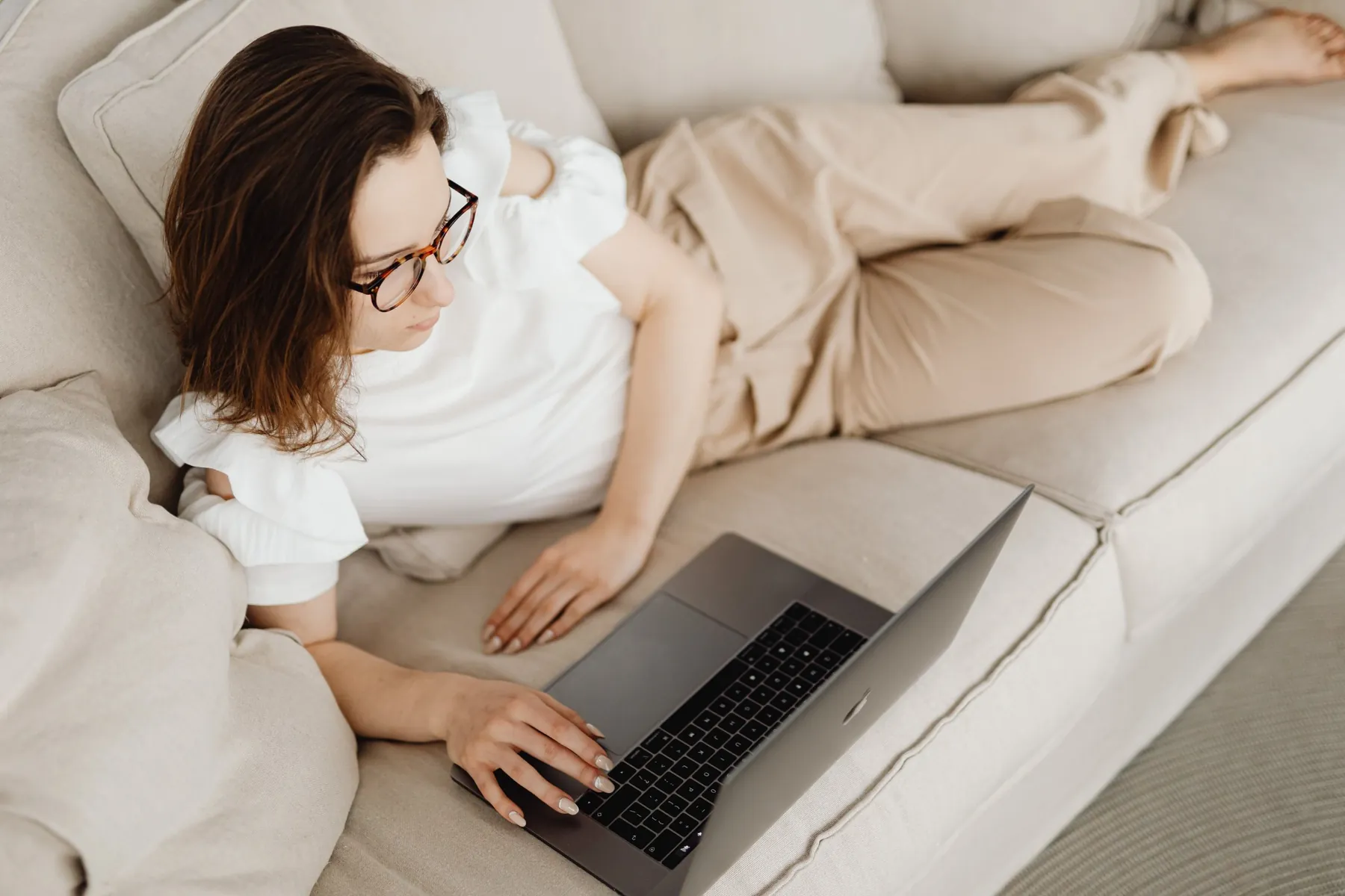 A woman relaxing on a sofa, watching a course on her laptop