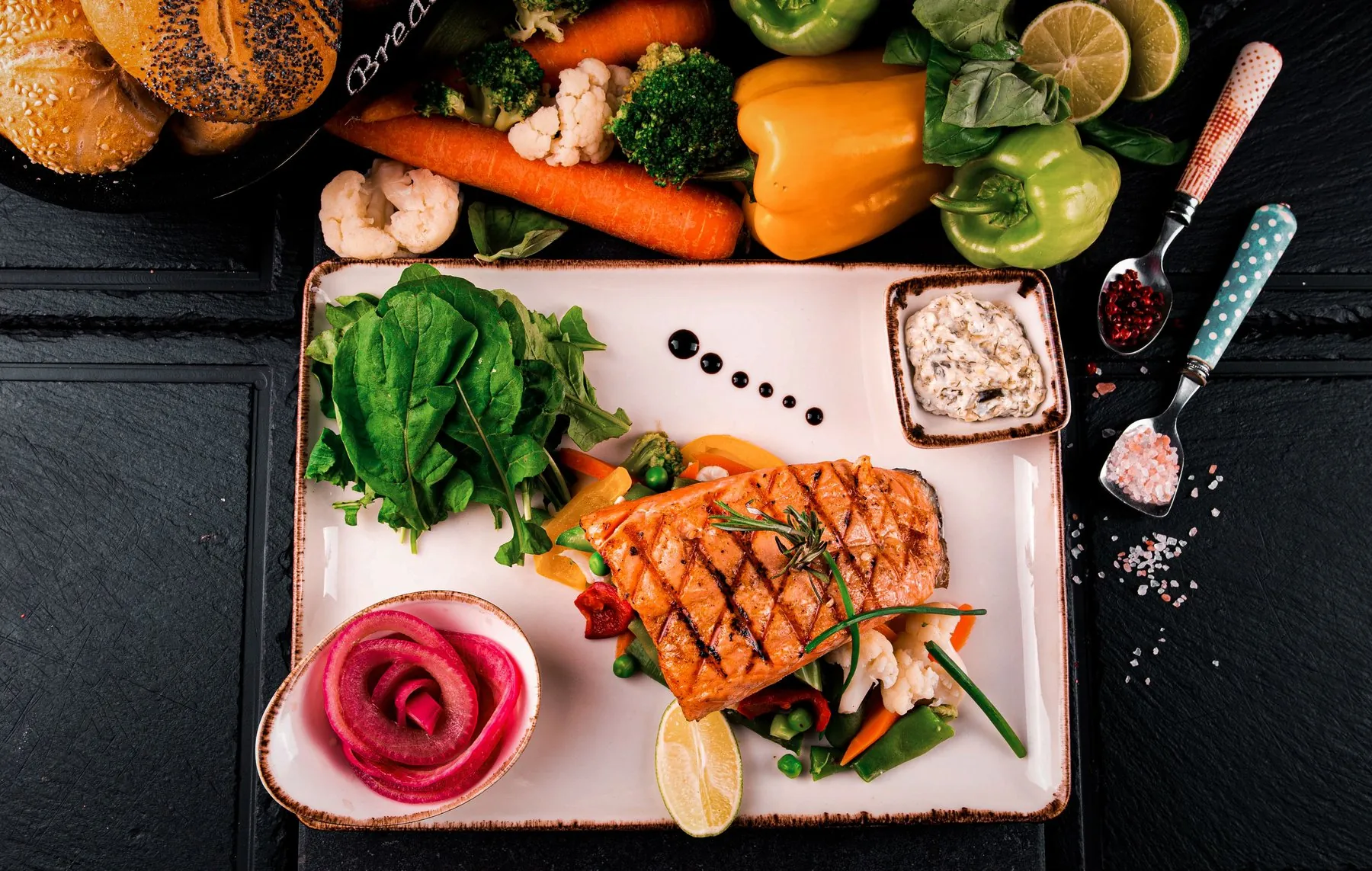 Grilled salmon with fresh vegetables and leafy greens on a white plate
