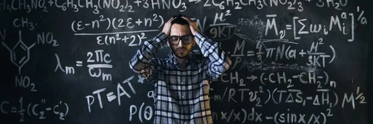 A stressed teacher holding his head in front of a chalkboard full of equations
