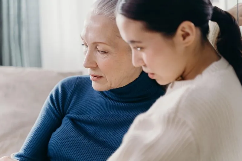 A young woman sitting closely beside an older woman