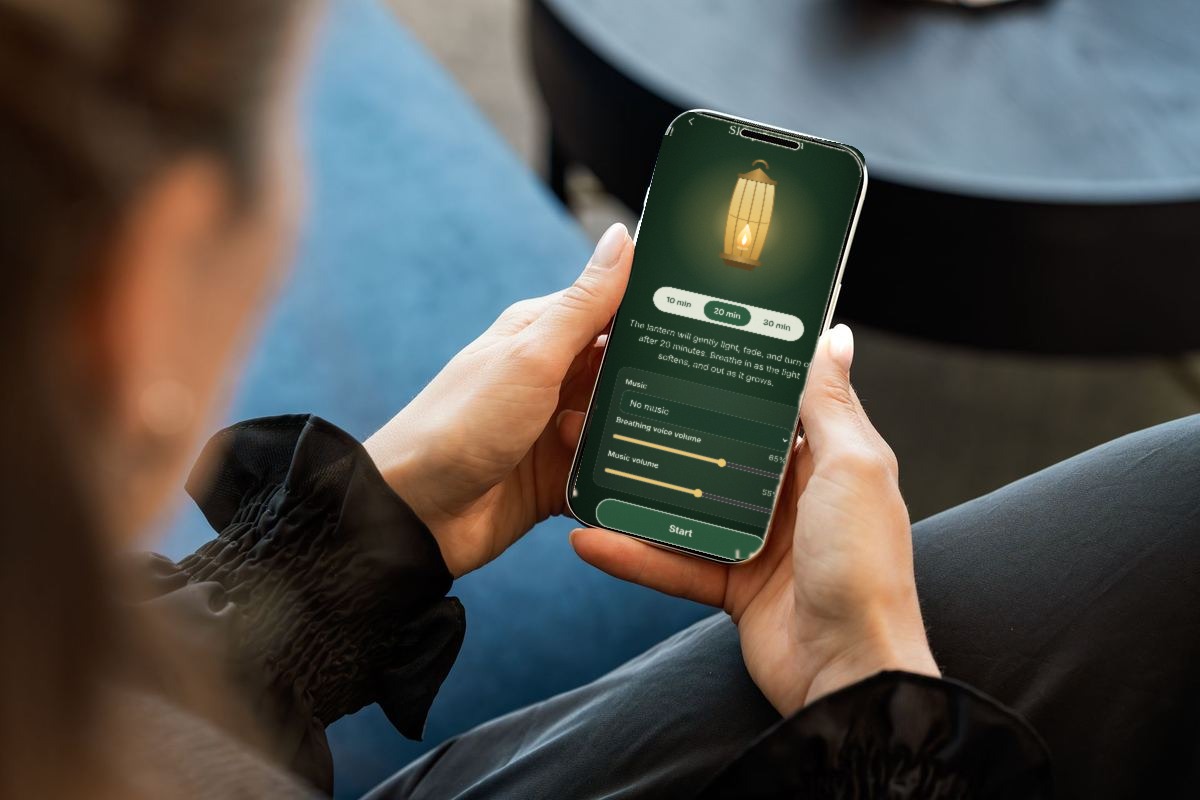 Hands holding a phone showing the InnerMotion Sleep Lantern, a glowing golden lantern with 10, 20 and 30 minute choices