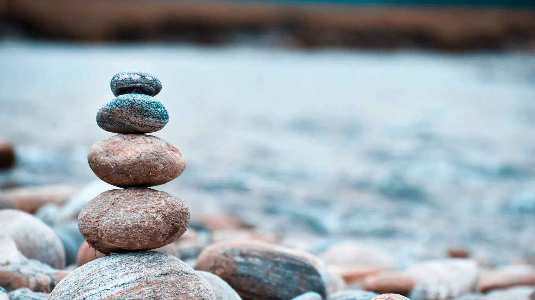 A small stack of smooth stones balanced on a pebble beach